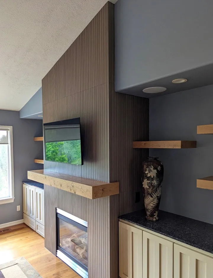 Floor-to-ceiling fluted feature wall with a wood mantel and inset fireplace