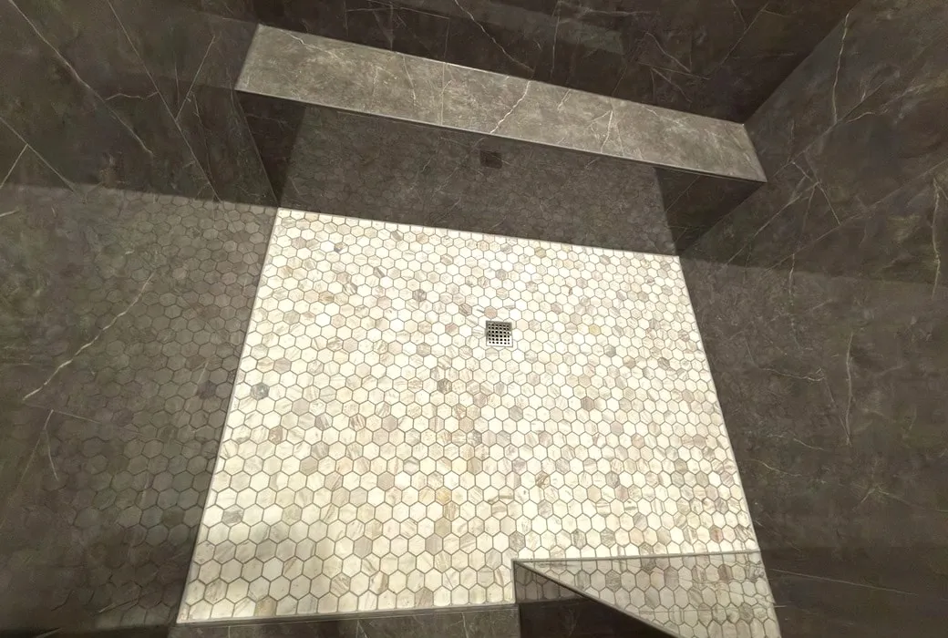 Marble hexagon mosaic shower floor pitched to the drain