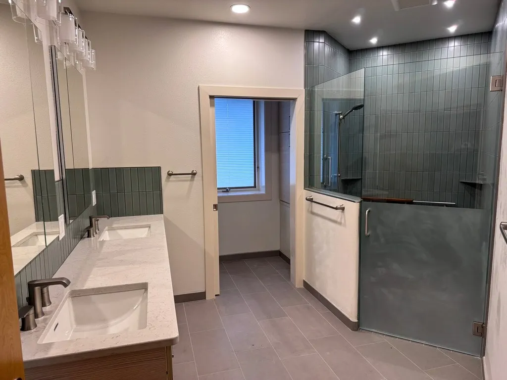 Master bath with double vanity, vertical stacked tile and a glass shower