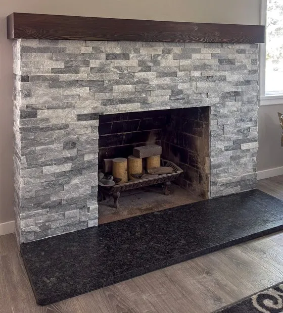 Stacked stone fireplace with a dark wood mantel